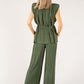 Woman wearing a green pleated jumpsuit on a white background