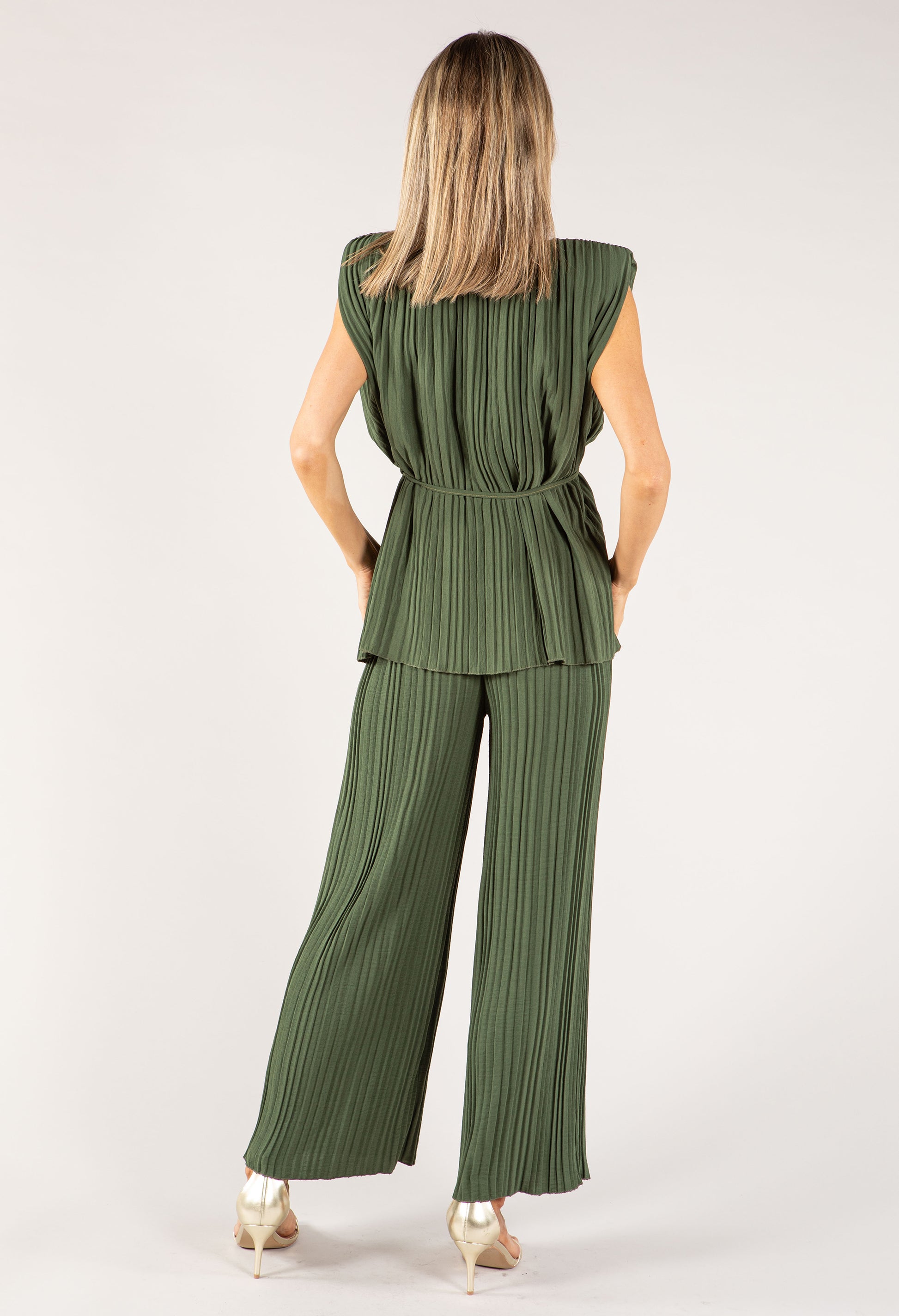 Woman wearing a green pleated jumpsuit on a white background