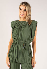 Woman wearing a green pleated top and pants on a white background