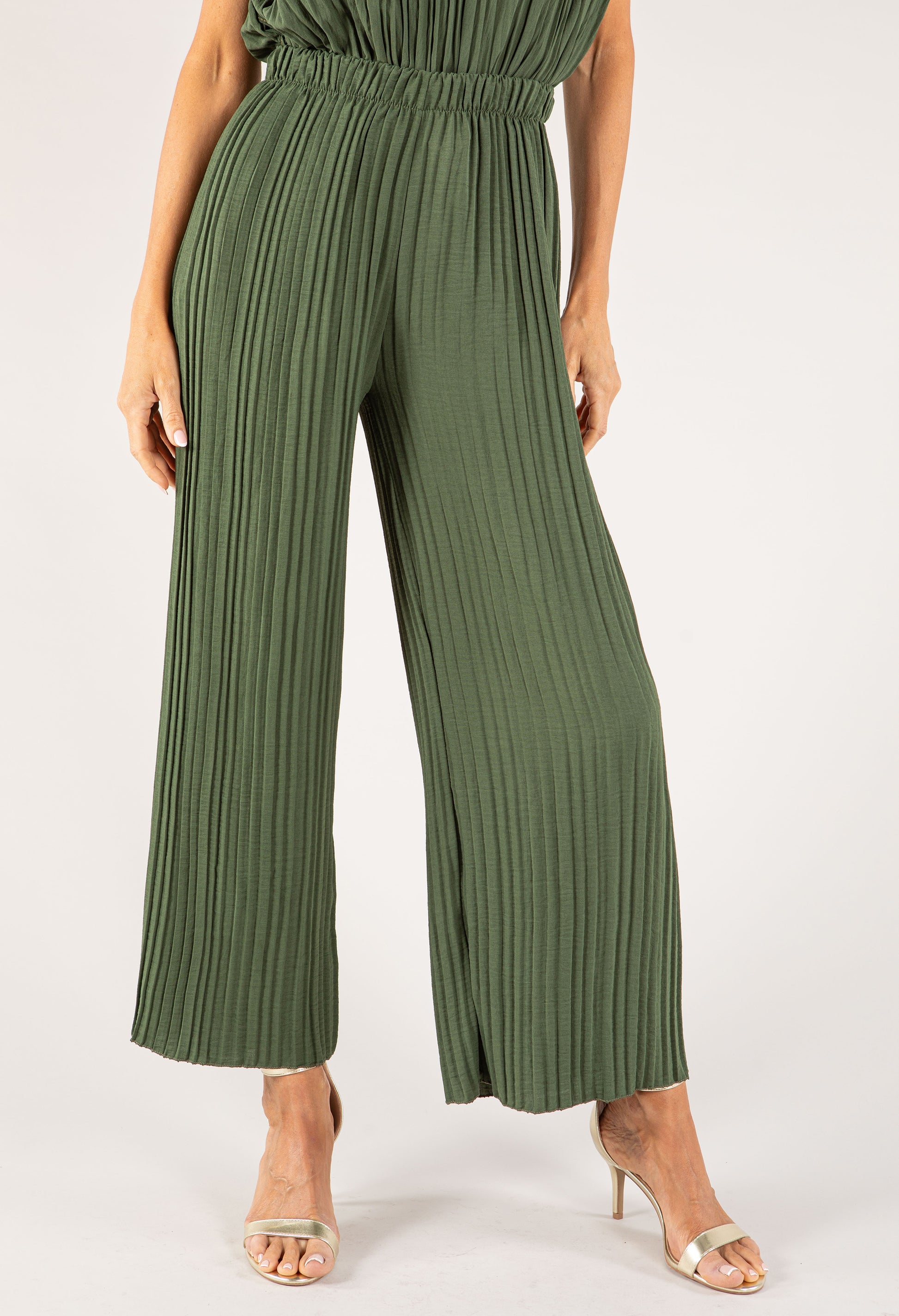 Green pleated jumpsuit worn by a person on a white background
