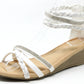 White wedge sandal with braided design on a white background