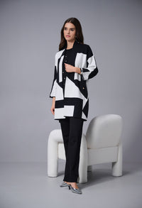 Woman wearing a black and white patterned outfit sitting on a white chair against a gray background