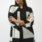 Woman wearing a black and white patterned coat on a white background