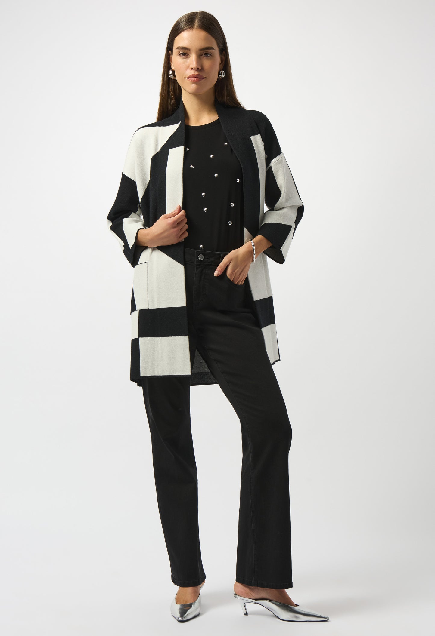 Woman wearing a black and white striped coat over a black outfit on a white background