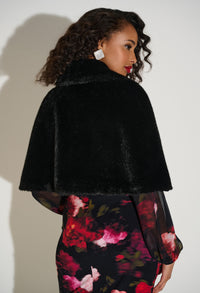 Woman wearing a black fur Capelet over a floral dress against a white background