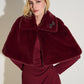 Woman wearing a burgundy fur stole over a dress against a white background