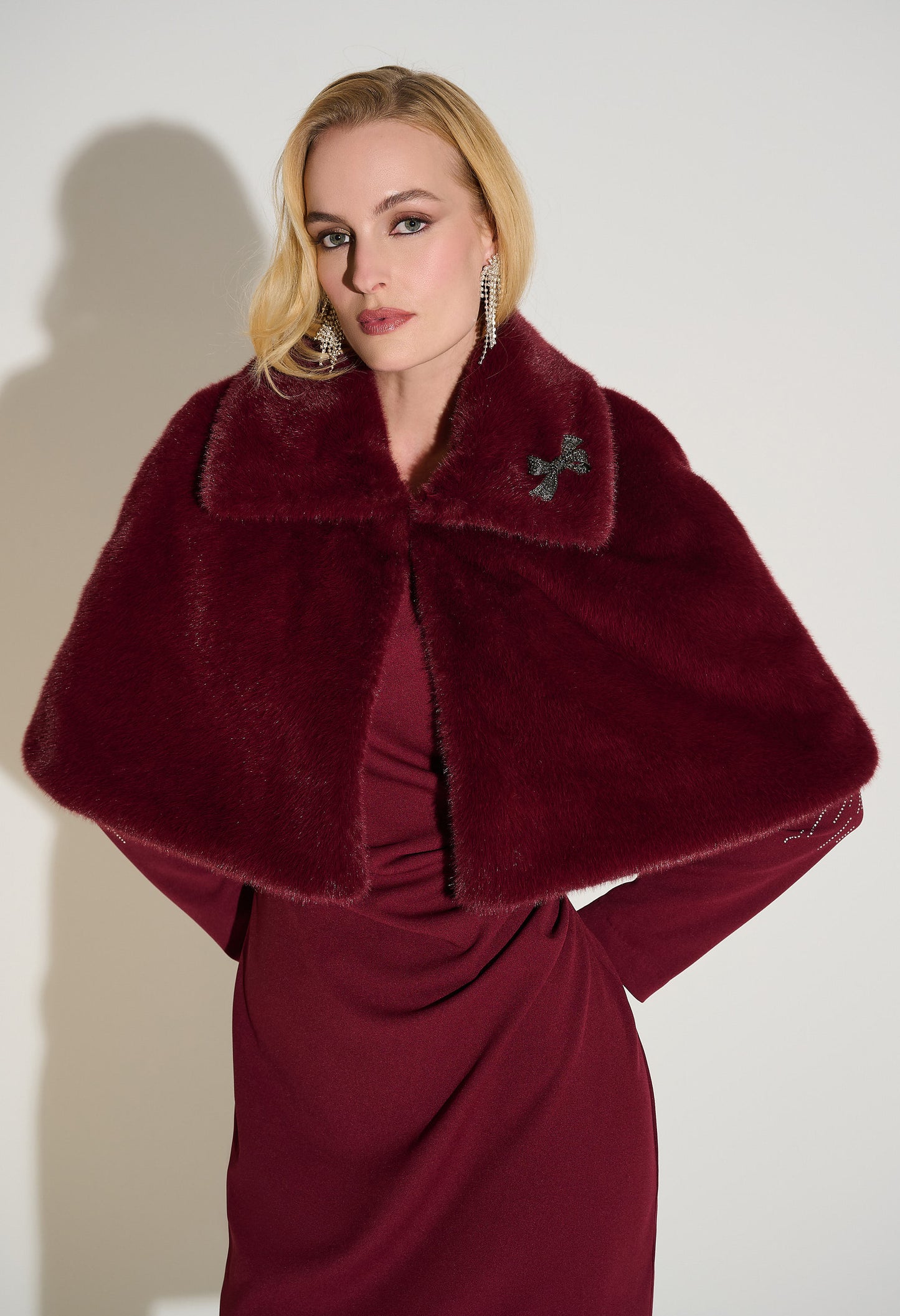 Woman wearing a burgundy fur stole over a dress against a white background