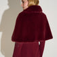 Woman wearing a burgundy fur cape against a white background