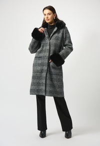 Woman wearing a long checkered coat with fur-lined hood on a white background