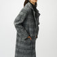 Woman wearing a gray checkered coat on a white background