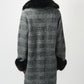 Woman wearing a checkered coat with fur trim on a white background