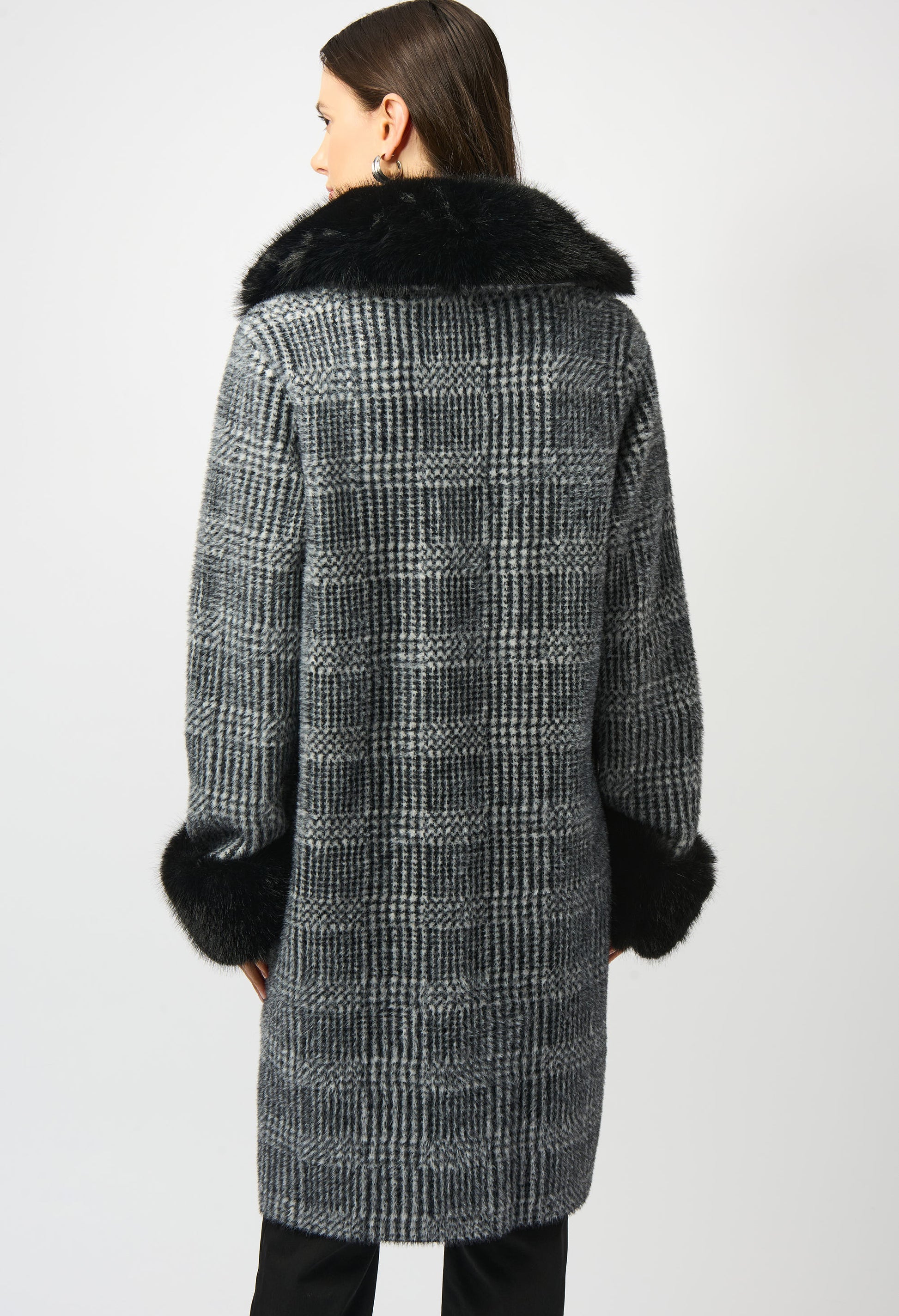 Woman wearing a checkered coat with fur trim on a white background