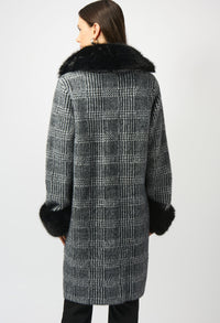 Woman wearing a checkered coat with fur trim on a white background