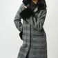 Woman wearing a checkered coat with black fur trim on a white background