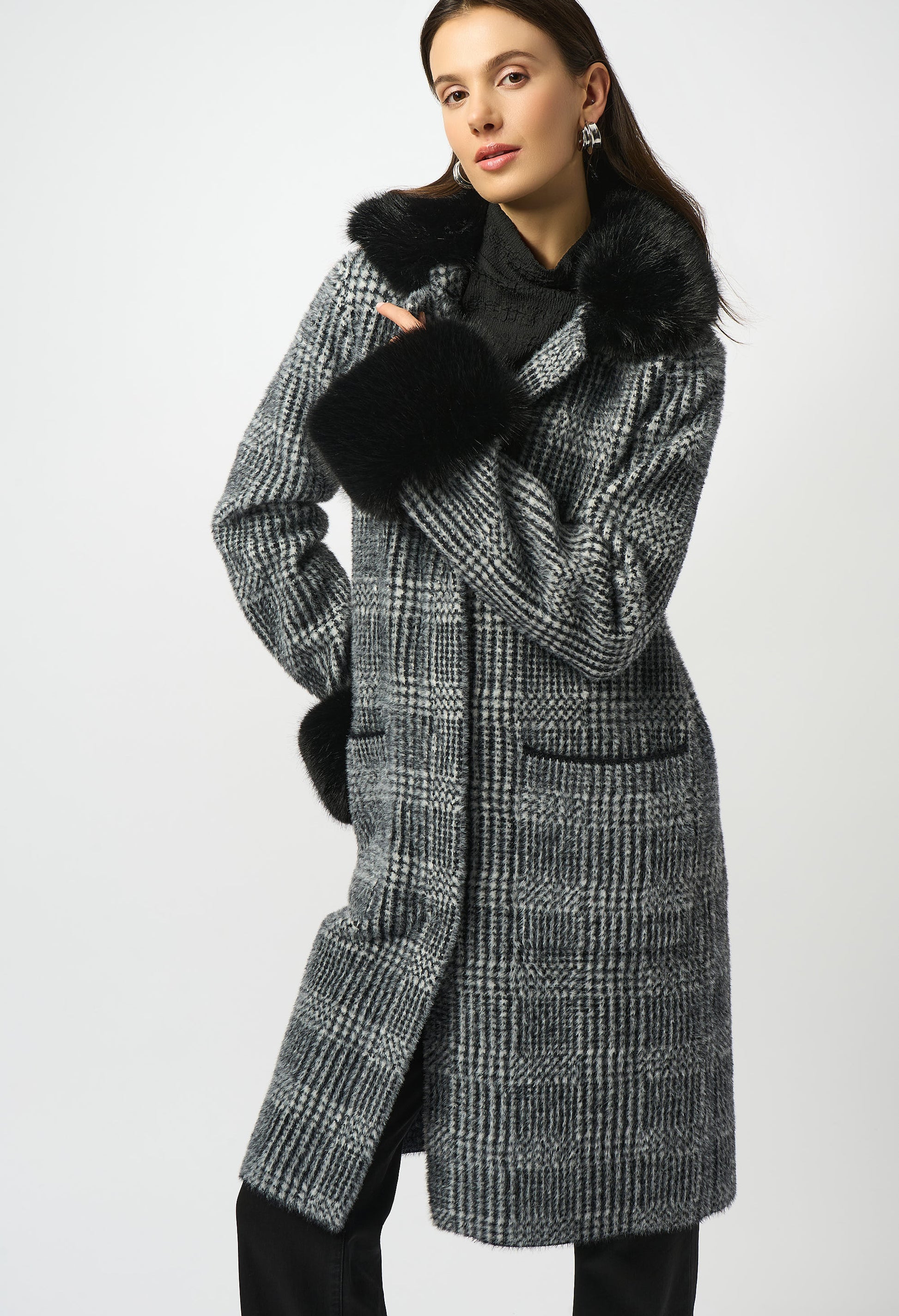 Woman wearing a checkered coat with black fur trim on a white background