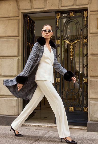 Woman in stylish outfit walking past a decorative door.