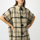Woman wearing a plaid poncho with black buttons on a white background