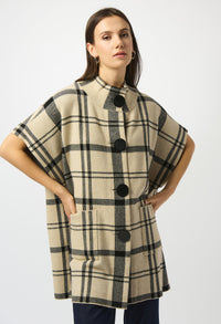 Woman wearing a plaid poncho with black buttons on a white background