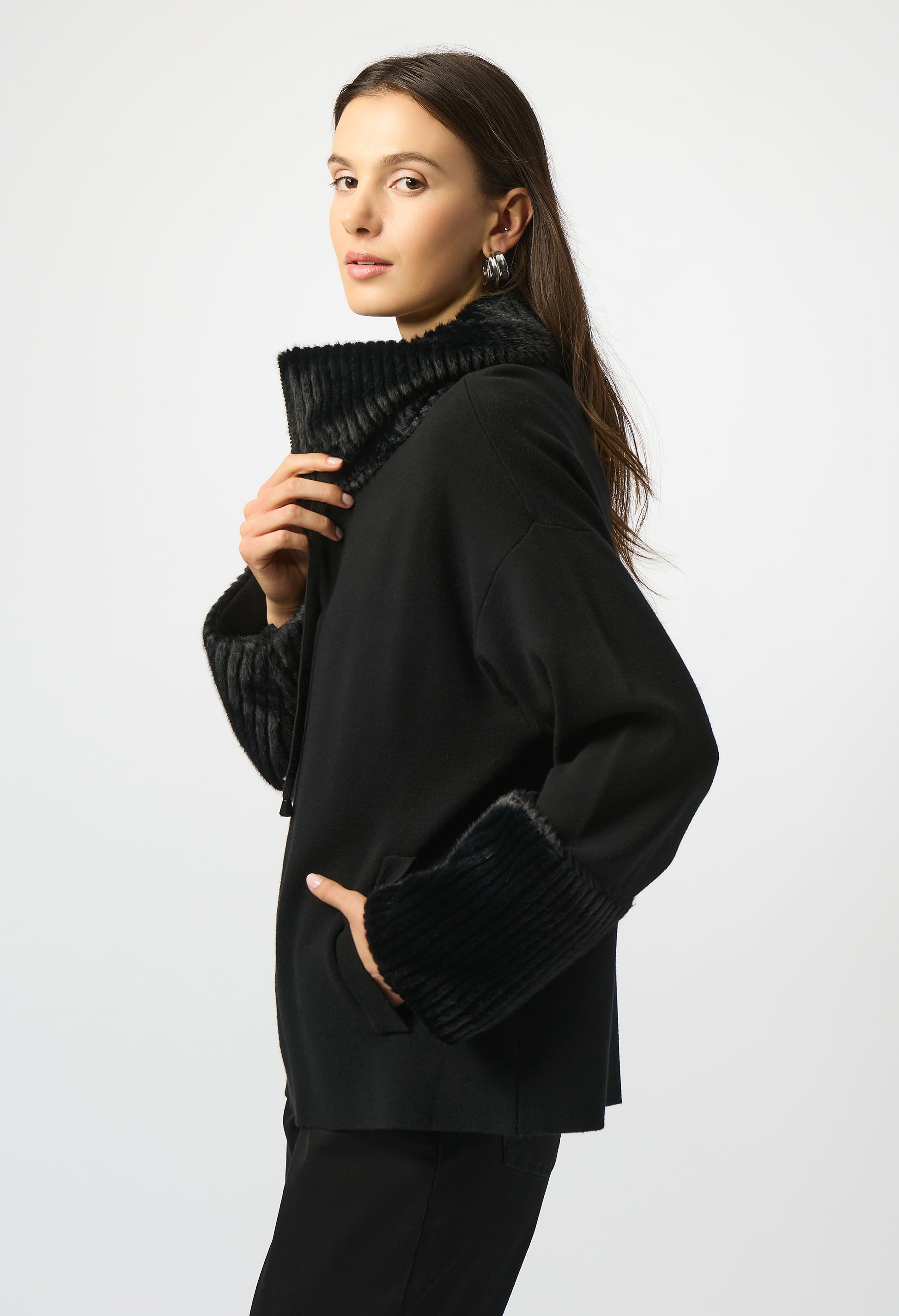 Woman wearing a black outfit with a textured collar against a white background