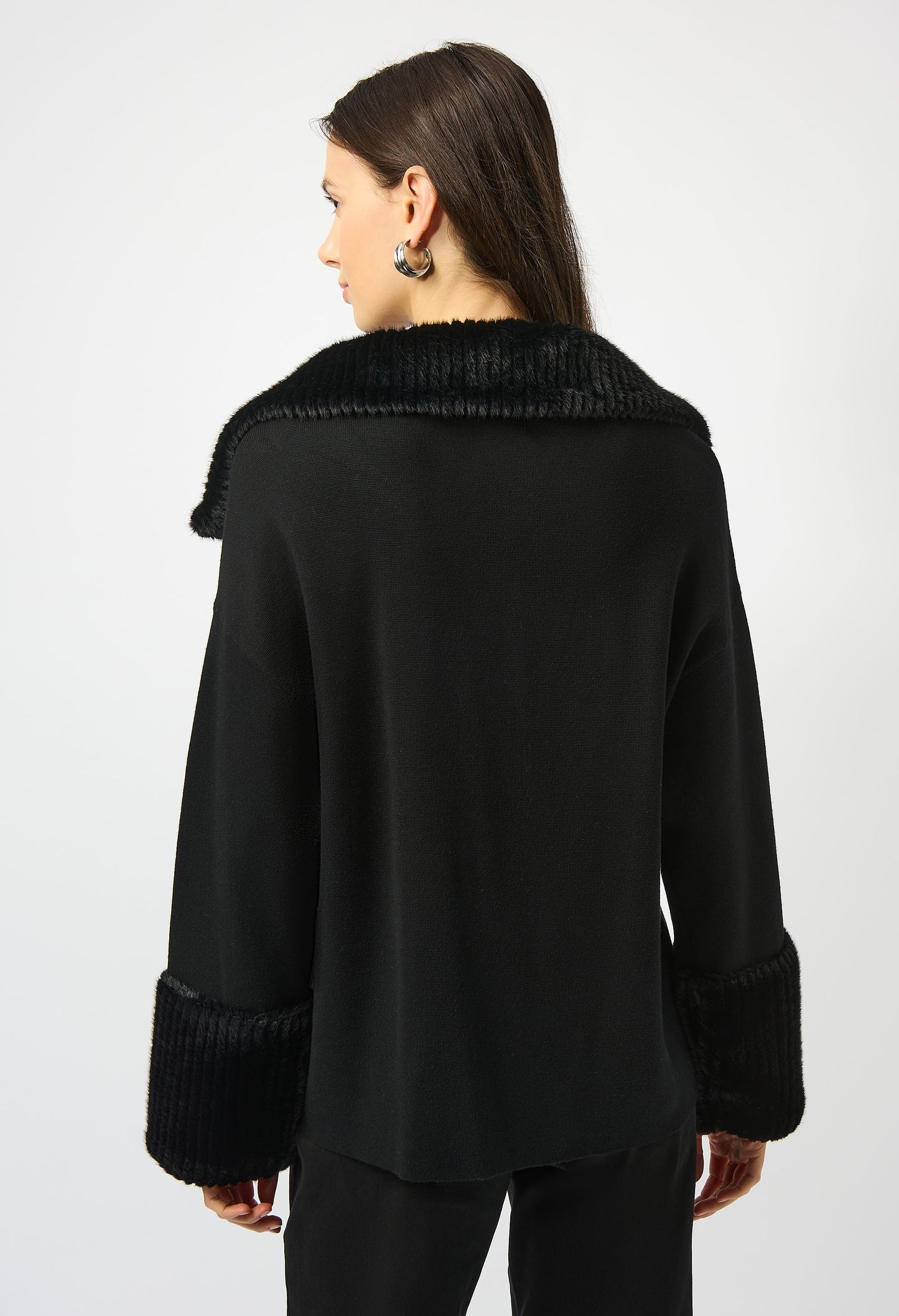 Person wearing a black coat with textured collar on a white background