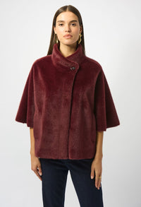 Woman wearing a burgundy cape coat against a white background