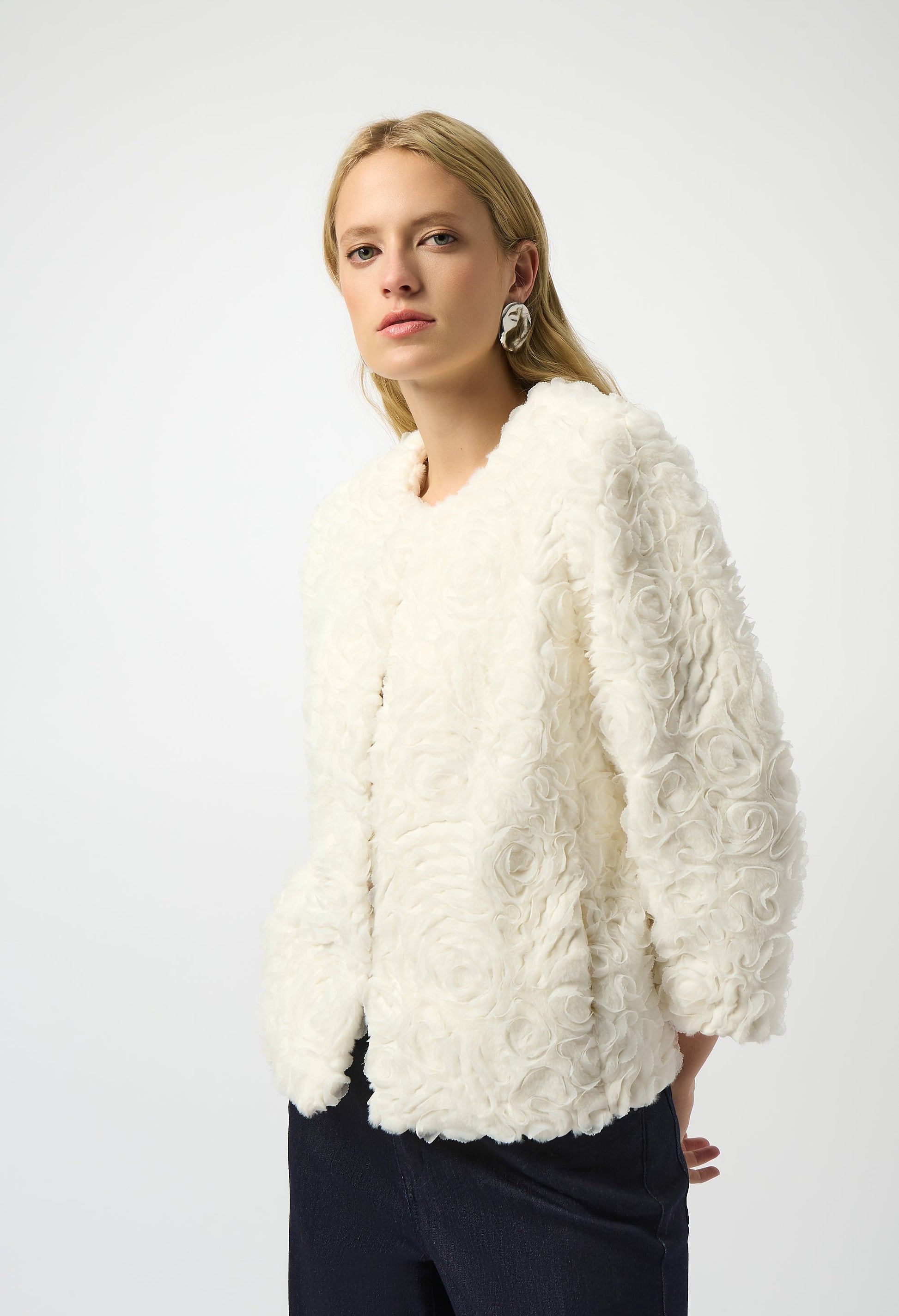 Woman wearing a white textured jacket against a white background