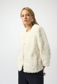 Woman wearing a white textured jacket against a white background