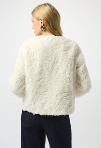 Woman wearing a textured white fur jacket on a plain background