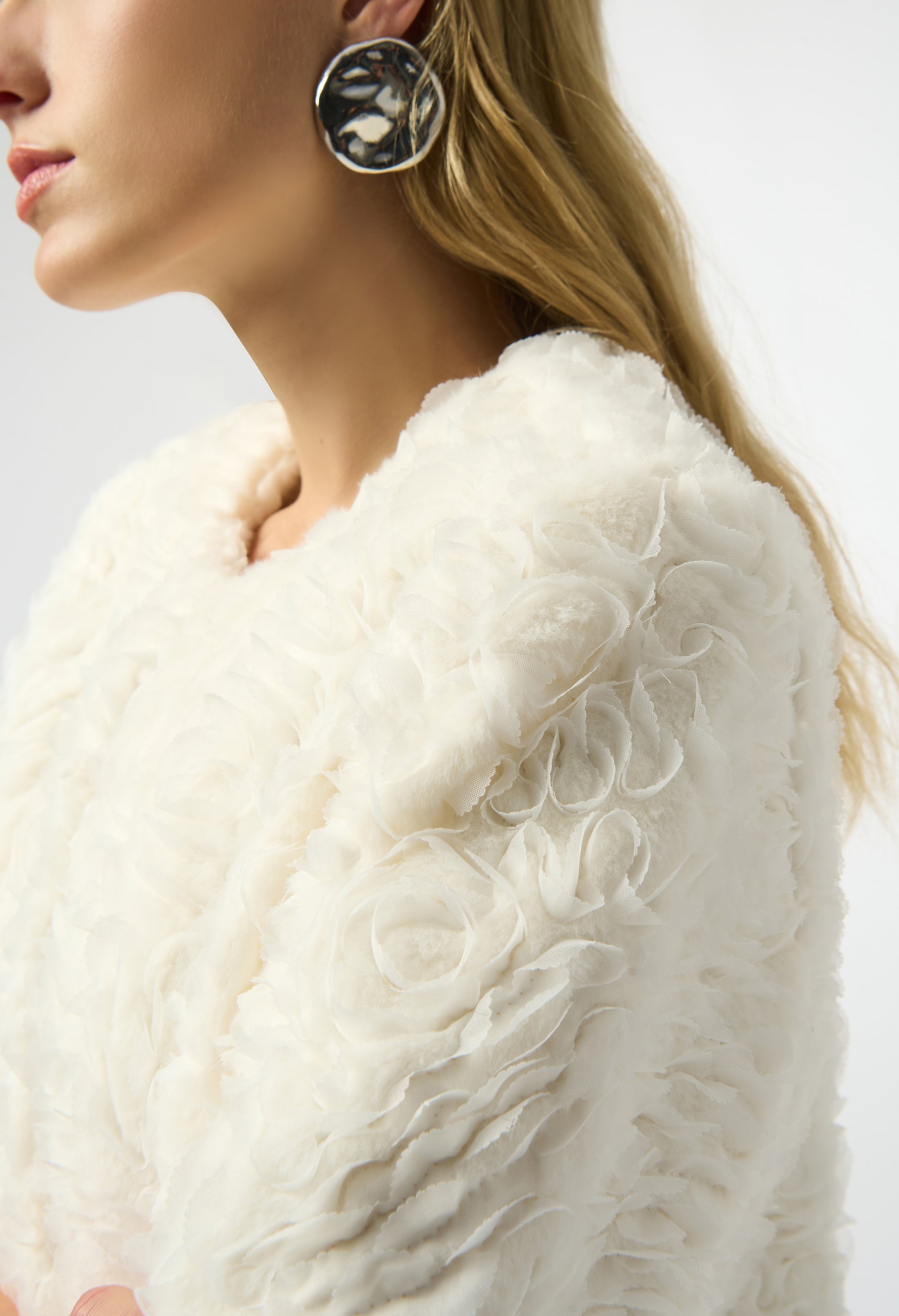 Close-up of a person wearing a white fur coat with a neutral background