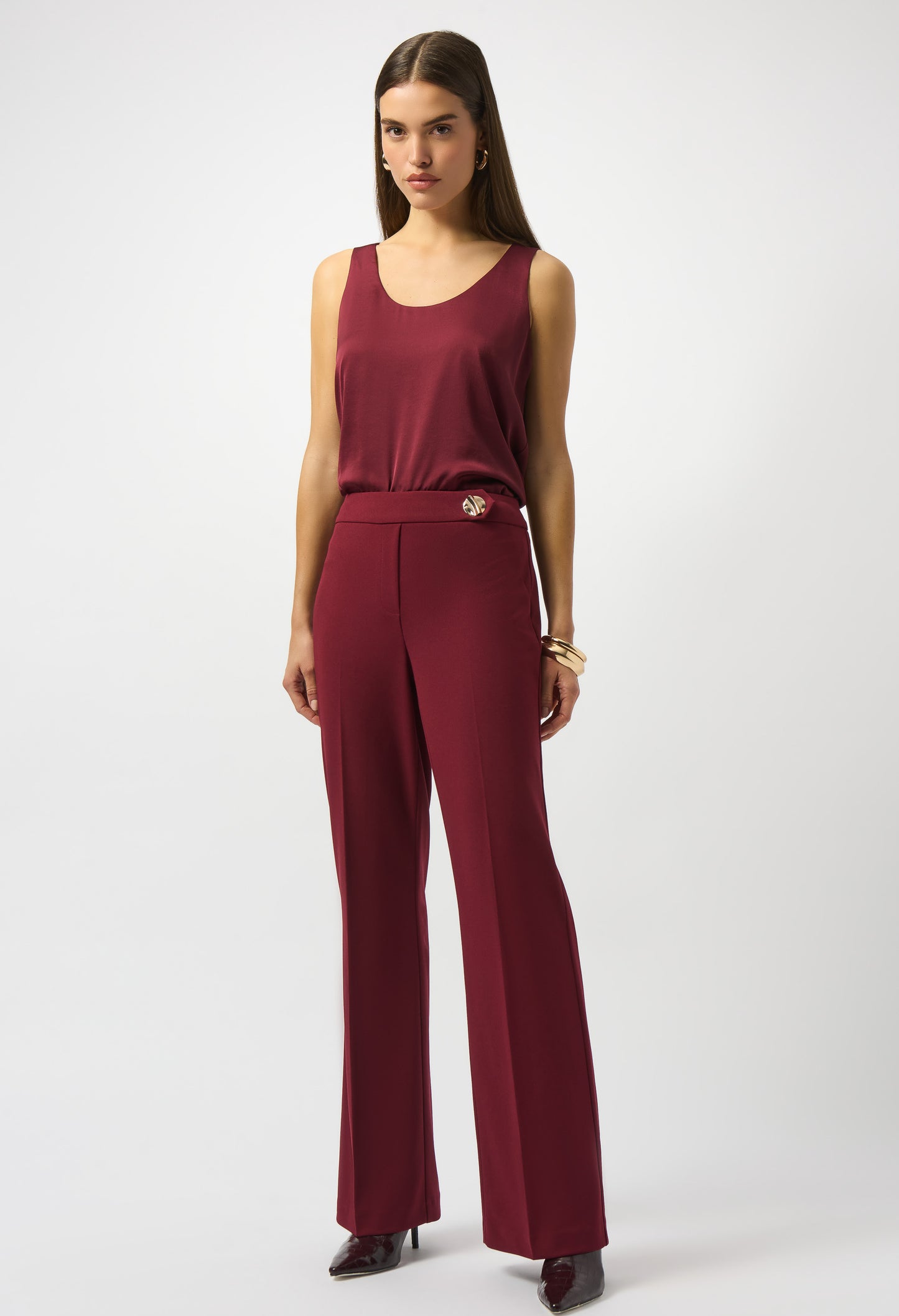 Woman wearing a burgundy sleeveless top and wide-leg pants on a white background