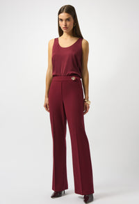 Woman wearing a burgundy sleeveless top and wide-leg pants on a white background