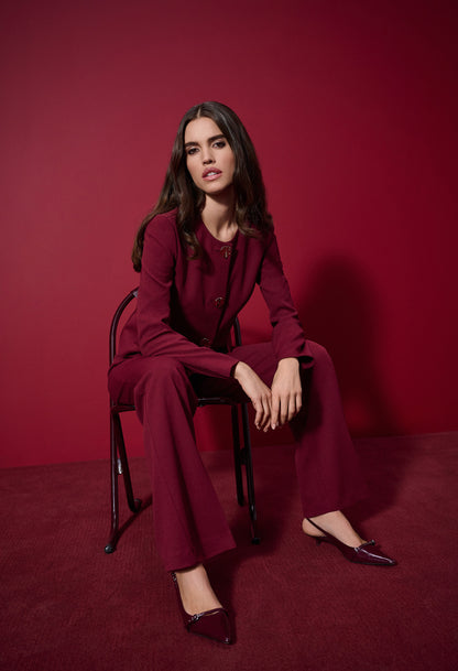 Woman in a red suit sitting on a chair against a red background