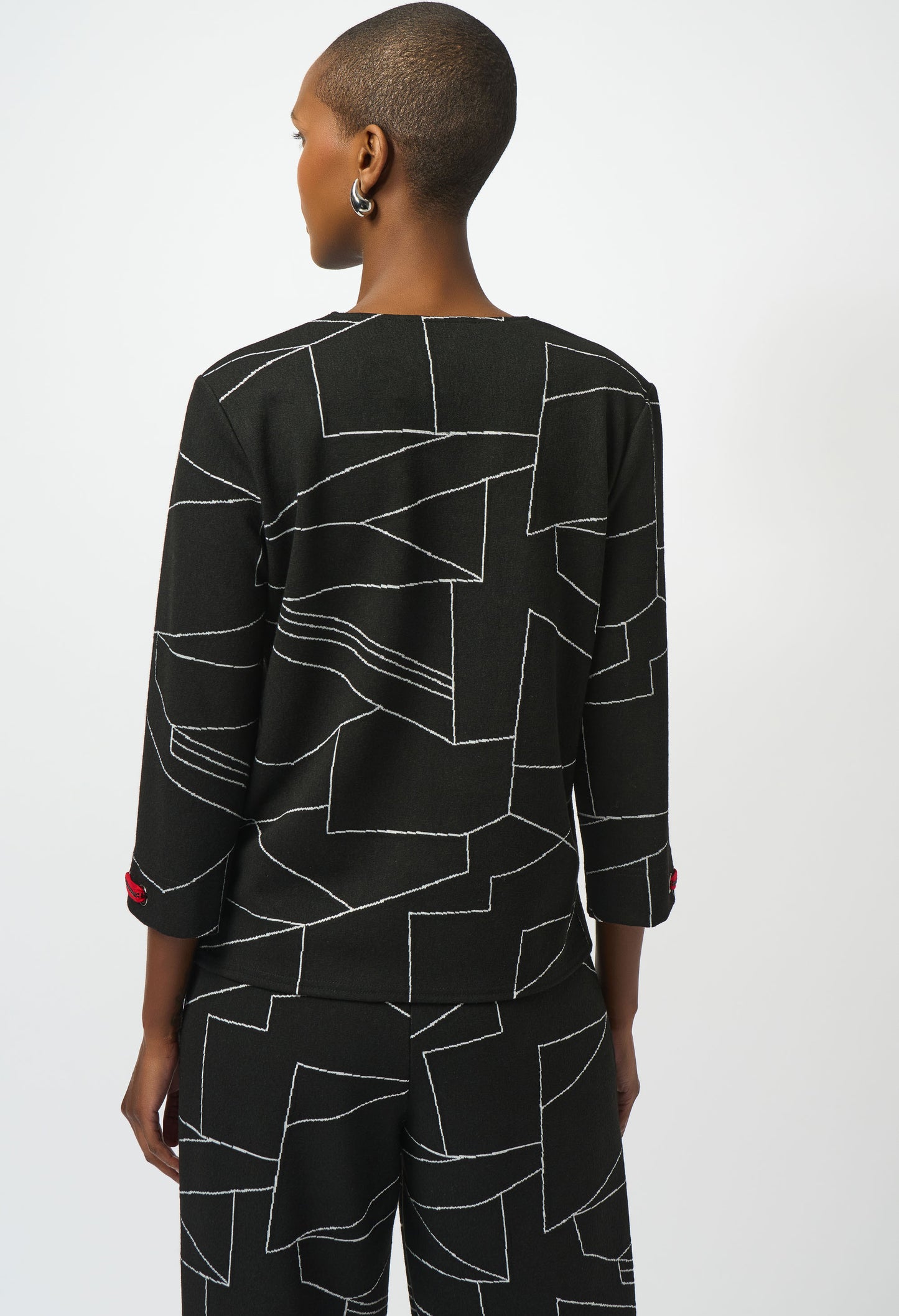 Person wearing a black outfit with geometric pattern on a white background