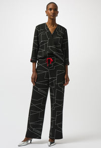 Woman wearing a black geometric patterned outfit with a red belt on a white background