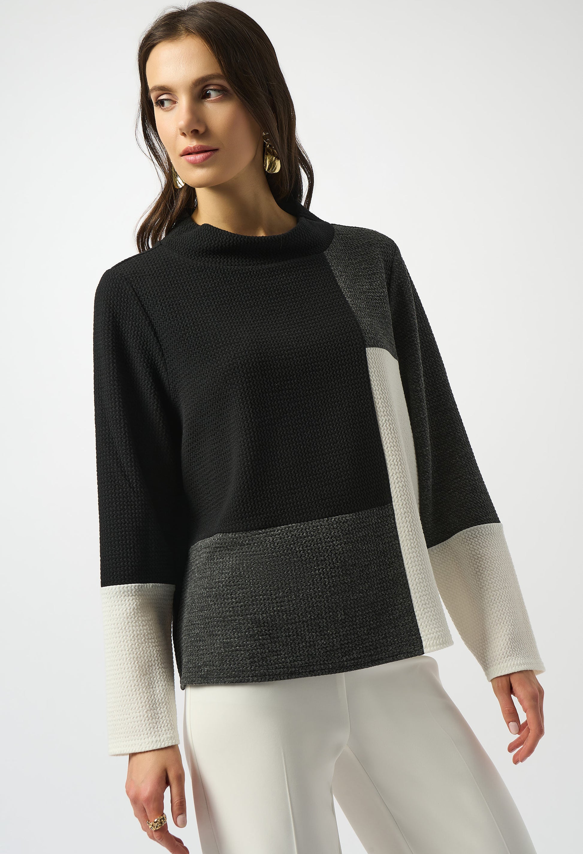 Woman wearing a black, gray, and white sweater on a white background