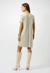 Woman wearing a beige dress and knee-high boots on a white background