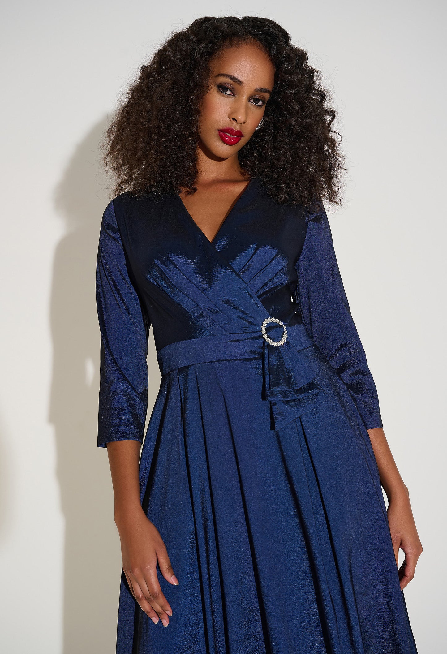 Woman wearing a blue dress with a belt against a white background