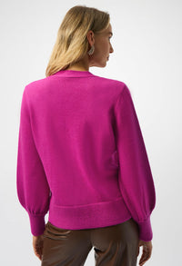 Person wearing a bright pink sweater on a white background