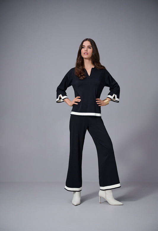 Woman wearing a black outfit with white trim on a gray background