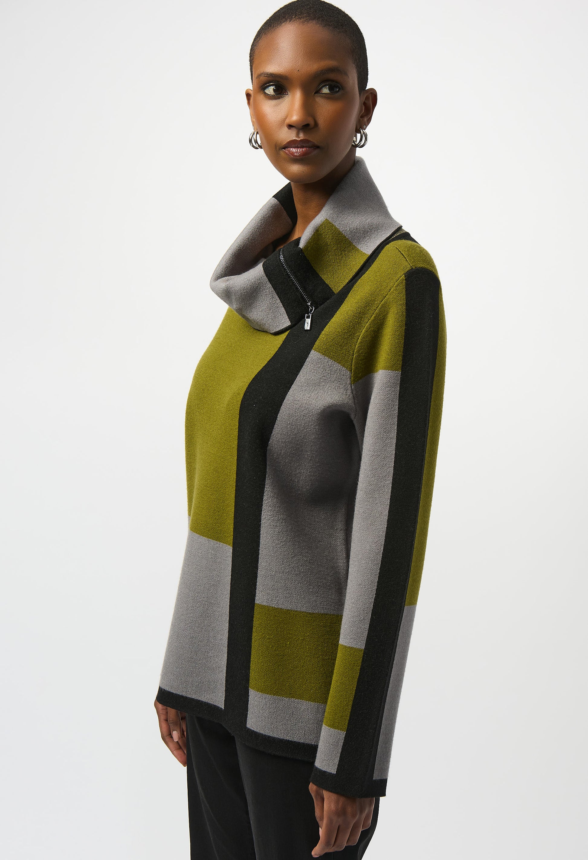 Woman wearing a color-blocked sweater with green, gray, and black stripes on a white background