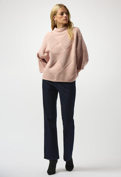 Woman wearing a pink sweater and dark pants on a white background