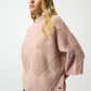 Woman wearing a pink textured sweater on a white background