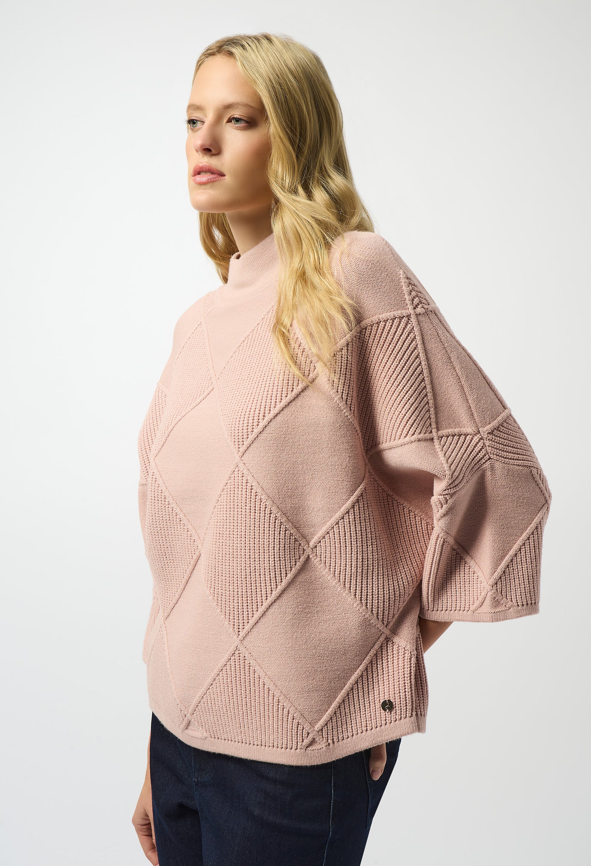 Woman wearing a pink textured sweater on a white background