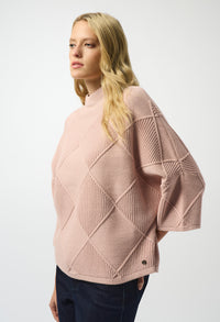 Woman wearing a pink textured sweater on a white background