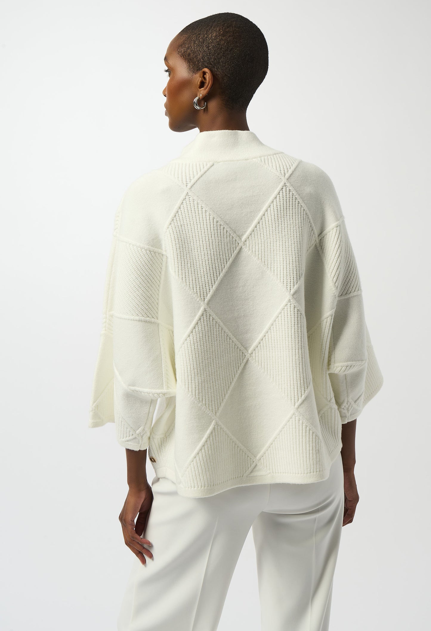 Person wearing a light-colored geometric patterned sweater on a white background