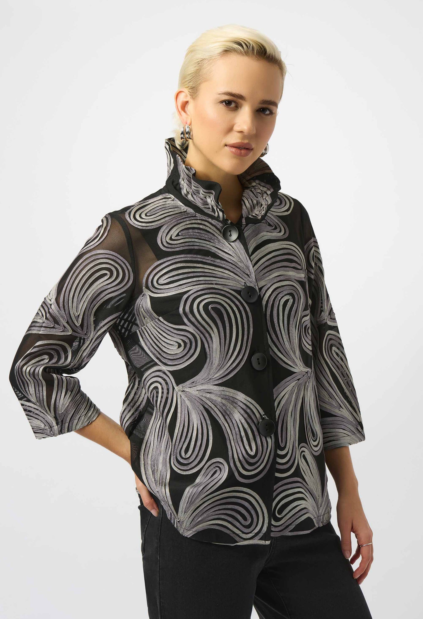 Woman wearing a black and gray patterned blouse against a white background