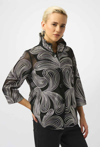 Woman wearing a black and gray patterned blouse against a white background