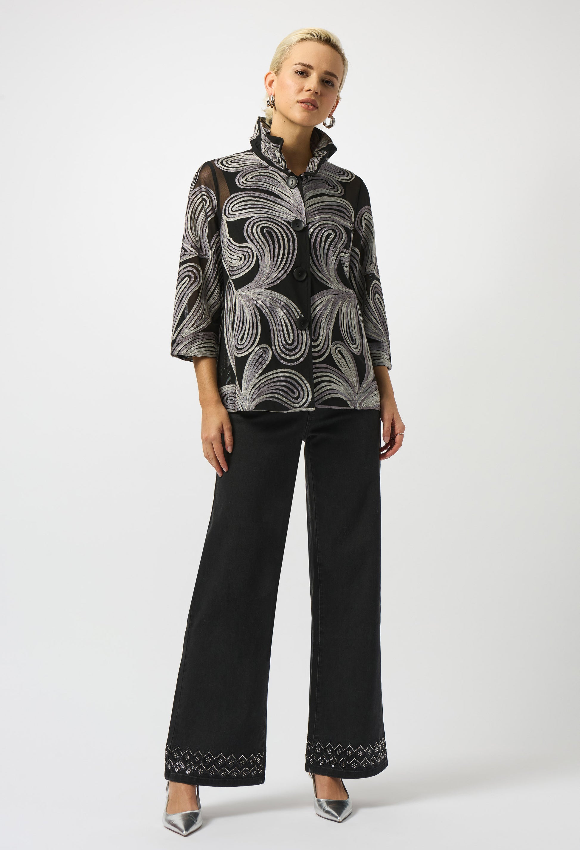 Woman wearing a patterned blouse and black pants on a white background