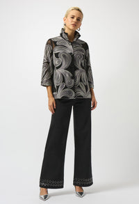 Woman wearing a patterned blouse and black pants on a white background