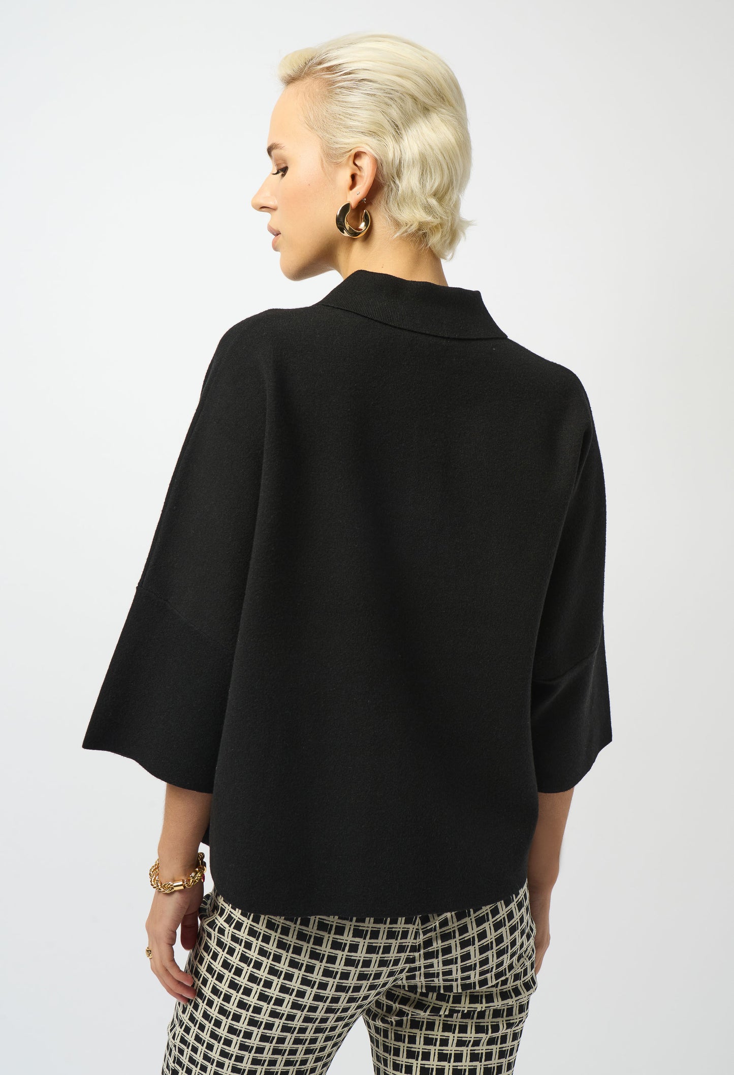 Person wearing a black jacket and patterned pants on a white background